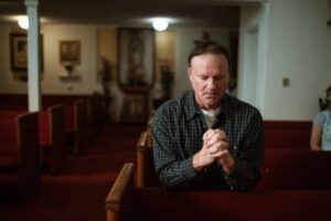 man sitting in a church pew praying